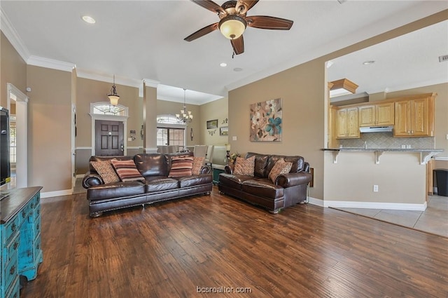 living room featuring crown molding, dark hardwood / wood-style flooring, and ceiling fan with notable chandelier