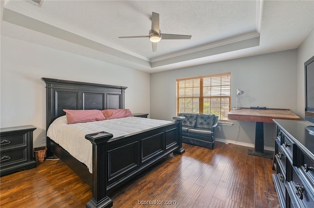 bedroom featuring ceiling fan, a tray ceiling, ornamental molding, a textured ceiling, and dark hardwood / wood-style flooring