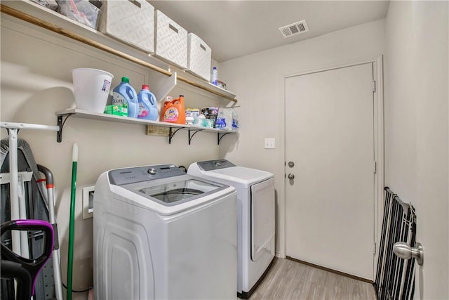 clothes washing area featuring washer and dryer and light hardwood / wood-style floors