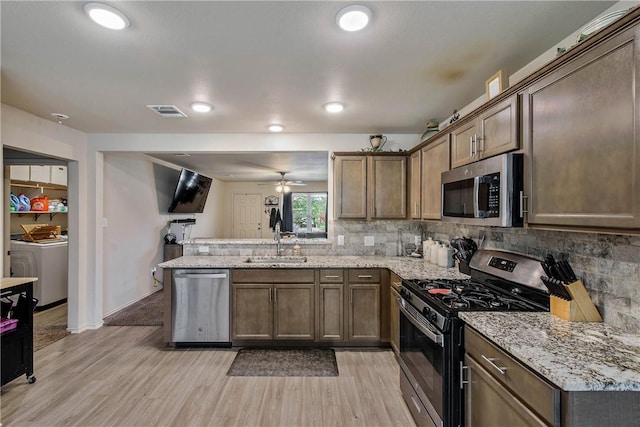 kitchen with sink, washer and clothes dryer, stainless steel appliances, tasteful backsplash, and light hardwood / wood-style floors