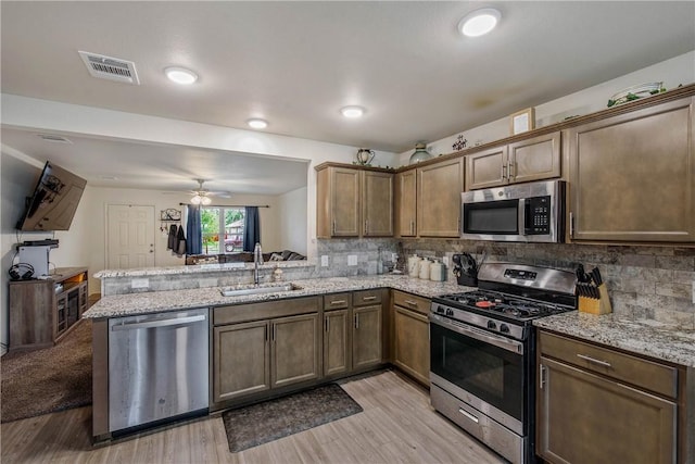 kitchen featuring sink, decorative backsplash, kitchen peninsula, and appliances with stainless steel finishes