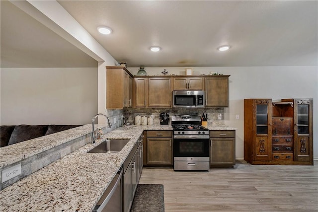 kitchen featuring stainless steel appliances, light stone countertops, sink, and decorative backsplash