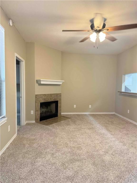 1305 W Villa Maria Rd Unit A-105, Bryan, TX 77801 - unfurnished living room featuring carpet floors, a tiled fireplace, and a ceiling fan