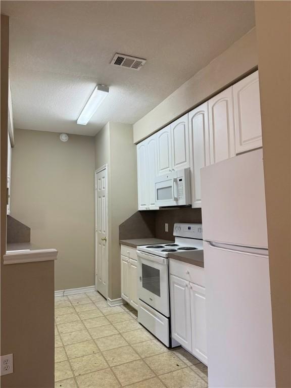 1305 W Villa Maria Rd Unit A-105, Bryan, TX 77801 - kitchen featuring white appliances, white cabinetry, dark countertops, and light floors