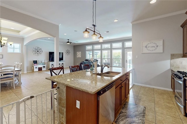 kitchen featuring appliances with stainless steel finishes, ceiling fan with notable chandelier, decorative light fixtures, and a kitchen island with sink