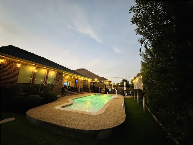 pool at dusk featuring a patio