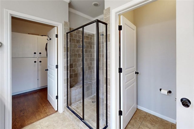 bathroom featuring tile patterned floors, crown molding, and a shower with door