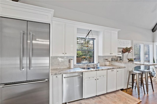 kitchen featuring stainless steel appliances, white cabinetry, tasteful backsplash, and sink