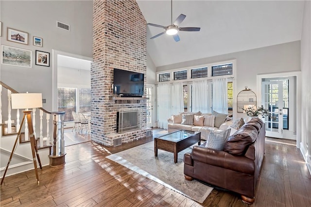 living room with hardwood / wood-style flooring, ceiling fan, a fireplace, and high vaulted ceiling