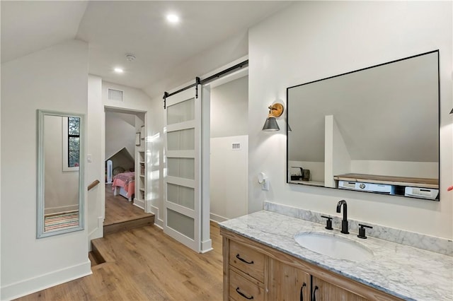 bathroom with hardwood / wood-style floors, vanity, and vaulted ceiling