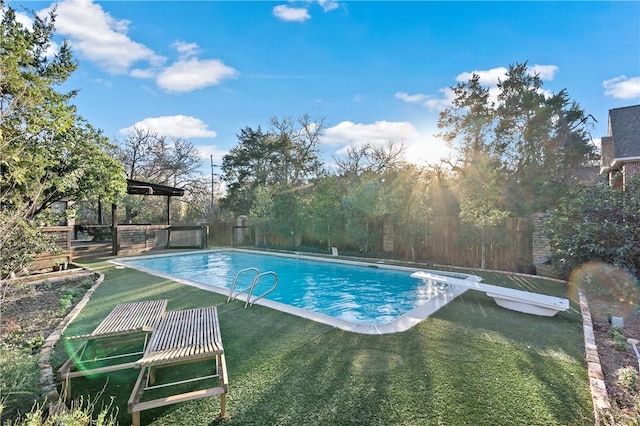 view of pool featuring a diving board and a lawn