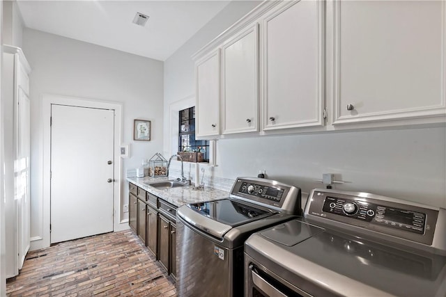 clothes washing area with cabinets, separate washer and dryer, and sink