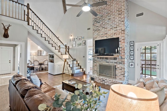 living room with ceiling fan, high vaulted ceiling, wood-type flooring, and a brick fireplace