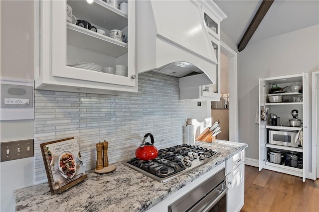 kitchen with backsplash, premium range hood, white cabinets, beam ceiling, and stainless steel appliances