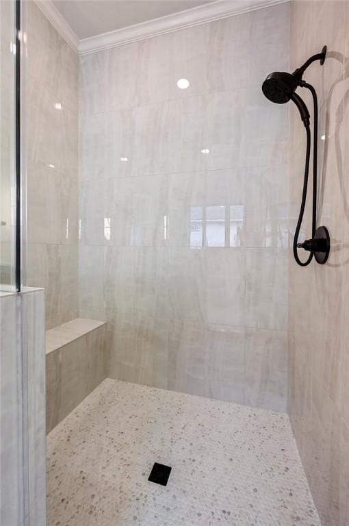 bathroom with tiled shower and ornamental molding