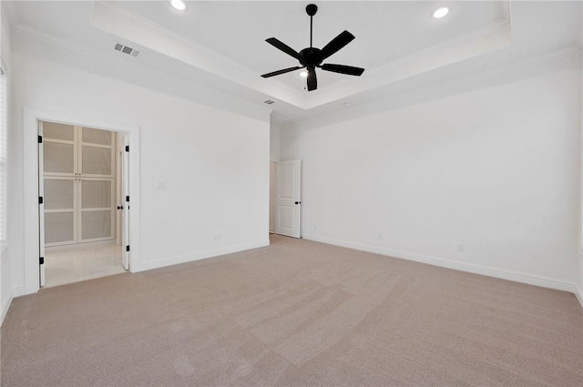 carpeted empty room featuring ceiling fan, ornamental molding, a towering ceiling, and a tray ceiling