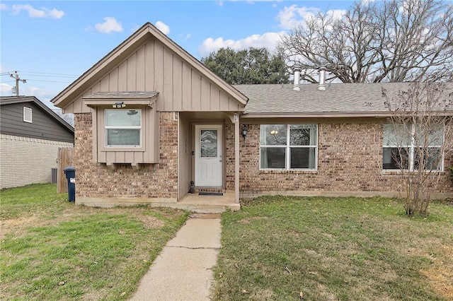 ranch-style home with board and batten siding, a front yard, roof with shingles, and brick siding