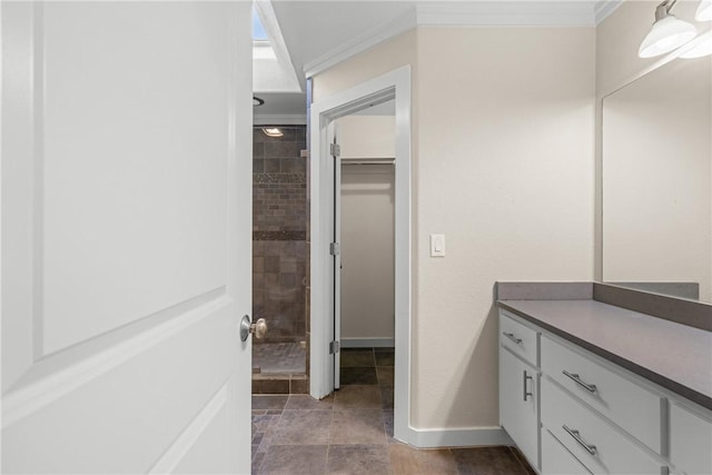 bathroom with vanity, ornamental molding, and tiled shower