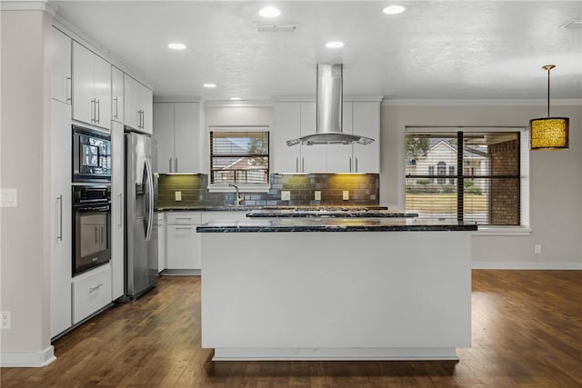 kitchen featuring pendant lighting, appliances with stainless steel finishes, white cabinets, exhaust hood, and dark stone counters