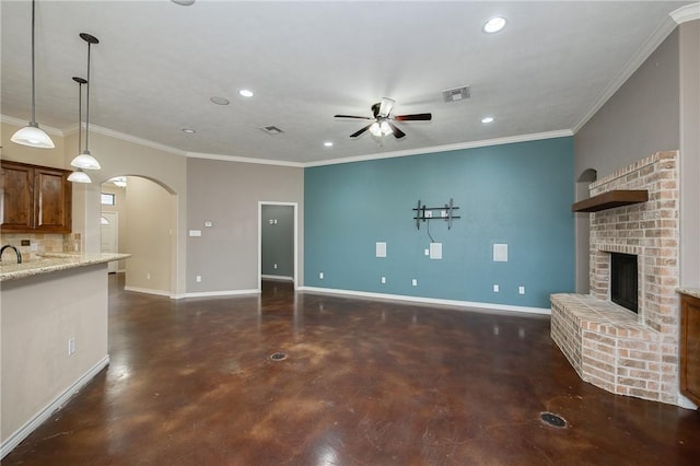 unfurnished living room featuring arched walkways, a brick fireplace, visible vents, and baseboards