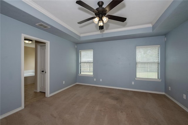 carpeted spare room featuring baseboards, visible vents, a raised ceiling, and crown molding