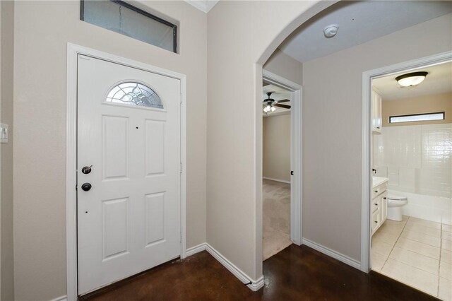 foyer featuring dark tile patterned floors, baseboards, and arched walkways