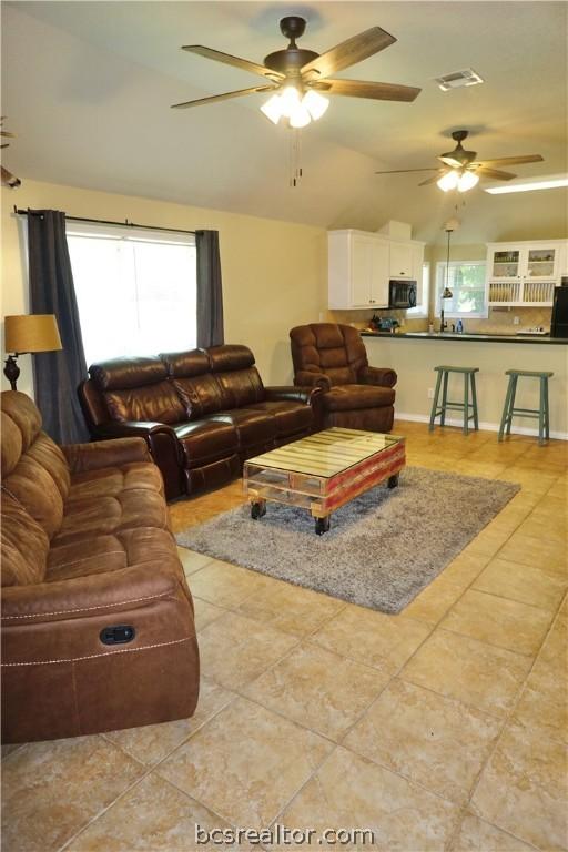 tiled living room featuring ceiling fan and lofted ceiling