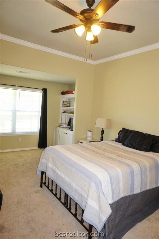 carpeted bedroom featuring ceiling fan and crown molding