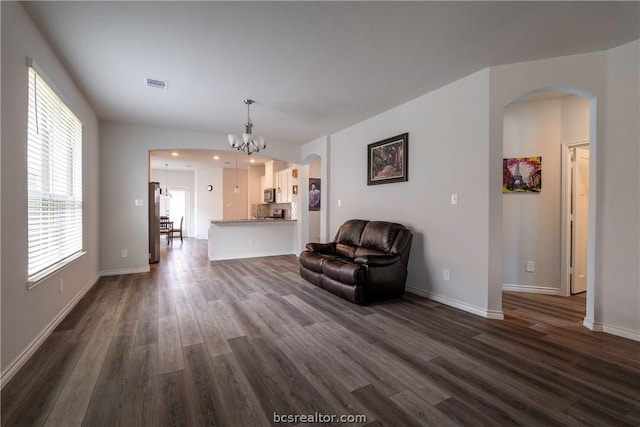 unfurnished living room featuring a chandelier and dark wood-type flooring