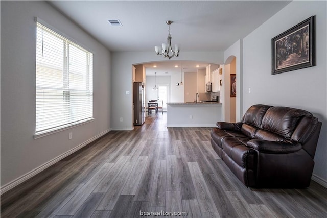 living room featuring plenty of natural light, dark wood-type flooring, and a chandelier