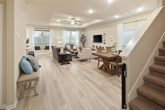 living room featuring ceiling fan, a raised ceiling, and light hardwood / wood-style flooring