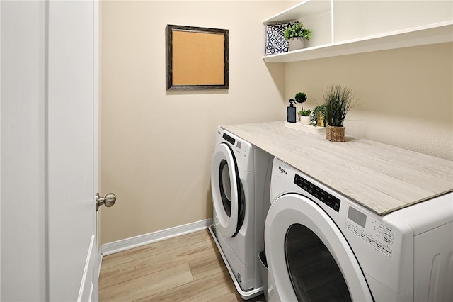 clothes washing area with washer and clothes dryer and light wood-type flooring