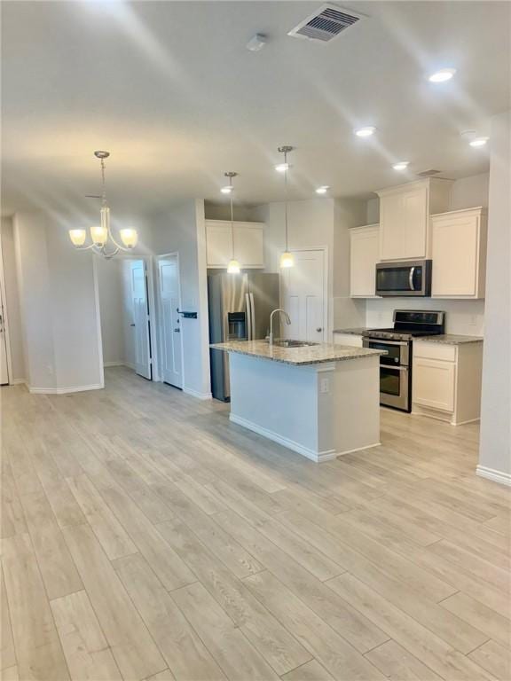 1074 Toledo Bend Dr, College Station, TX 77845 - kitchen with stainless steel appliances, light wood-style flooring, white cabinets, light stone counters, and recessed lighting