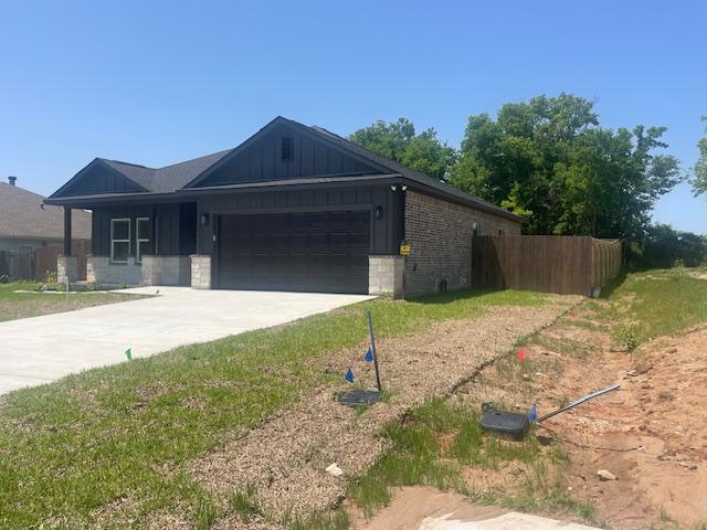 2303 White Wing Dr, Navasota, TX 77868 - view of front of property with board and batten siding, fence, an attached garage, and concrete driveway