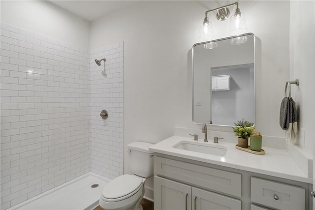 bathroom featuring a tile shower, toilet, and vanity