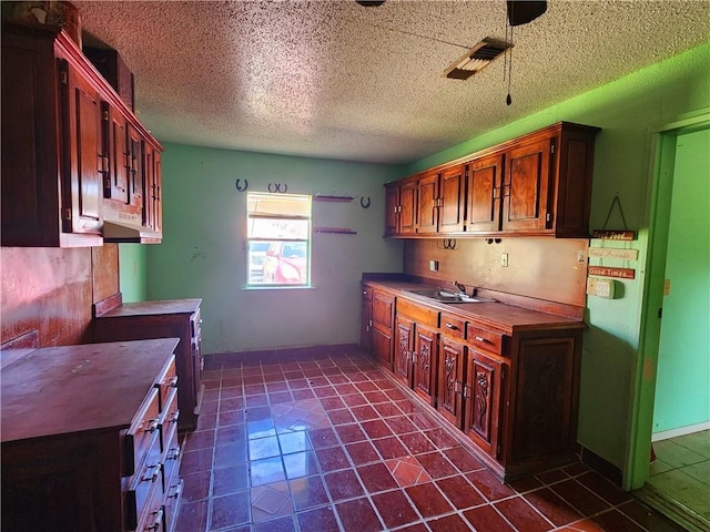 kitchen with dark tile patterned flooring, sink, and a textured ceiling