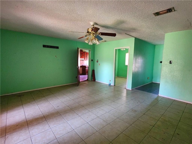 tiled spare room featuring a textured ceiling and ceiling fan