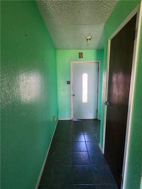 doorway featuring dark tile patterned floors and a textured ceiling