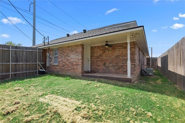 rear view of property with ceiling fan and a lawn