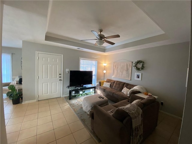 tiled living room featuring a tray ceiling and ceiling fan