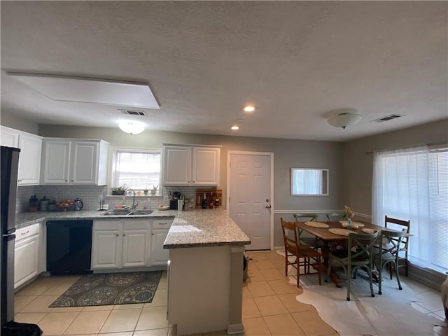 kitchen with white cabinetry, sink, dishwasher, light stone counters, and light tile patterned floors