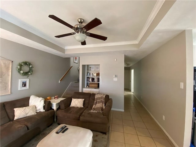 living room with ceiling fan, a raised ceiling, light tile patterned floors, and ornamental molding