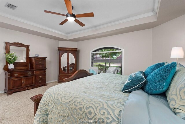 carpeted bedroom featuring a raised ceiling, ceiling fan, and crown molding