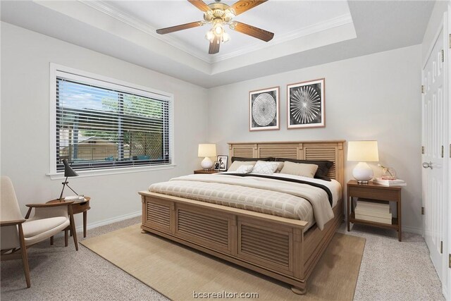 bedroom featuring a tray ceiling, ceiling fan, light colored carpet, and ornamental molding