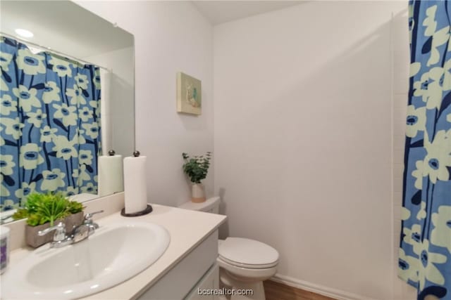 bathroom featuring hardwood / wood-style flooring, vanity, toilet, and walk in shower