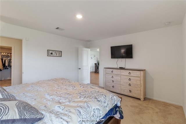 carpeted bedroom featuring a spacious closet and a closet