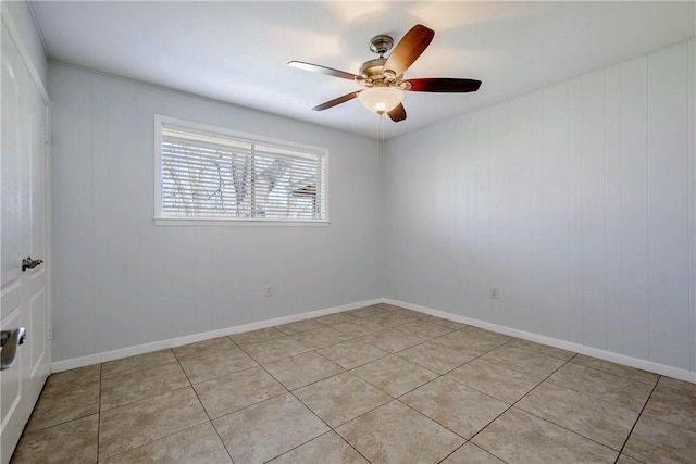 spare room featuring light tile patterned flooring, a ceiling fan, and baseboards