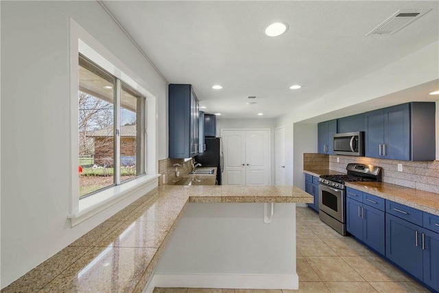 kitchen with visible vents, backsplash, tile counters, stainless steel appliances, and blue cabinets