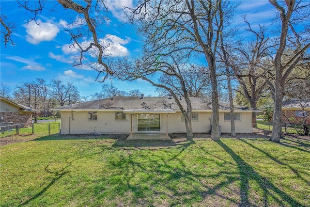 back of property with a lawn and fence