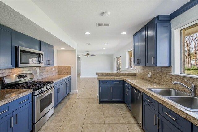 kitchen with visible vents, blue cabinetry, light tile patterned floors, appliances with stainless steel finishes, and a sink